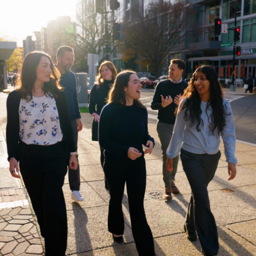 Six people walk down the street while talking to each other